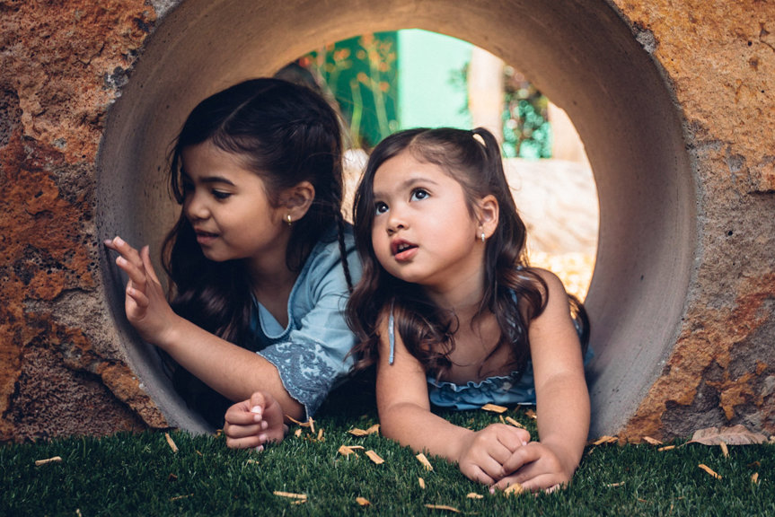 Two girls inside a rock tunnel outside