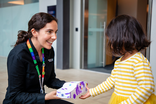 A child showing off their decorated cardboard car to the Road to Zero Learning Facilitator. 