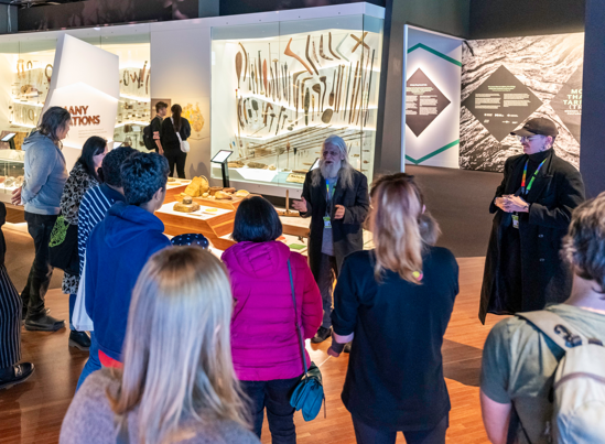 A tour guide leads a group of museum goers through an exhibition.