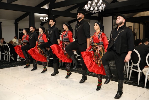 Turkish dancers on a stage dancing while surrounded by diners.