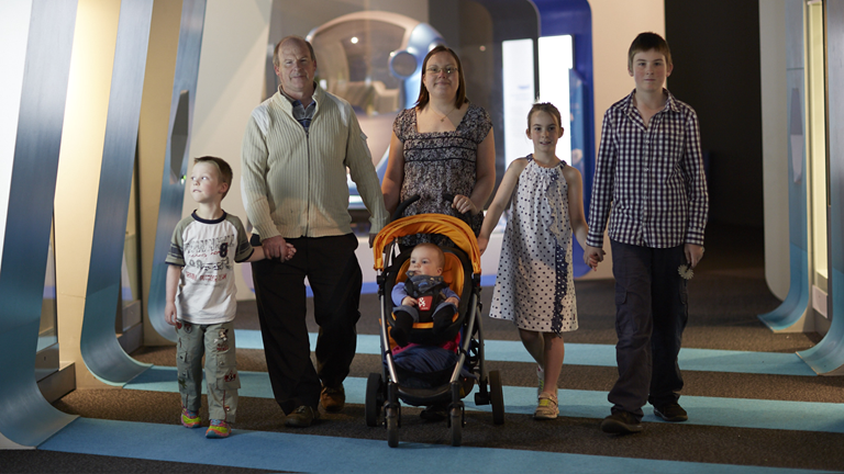 A family walking hand in hand through an exhibition at Scienceworks