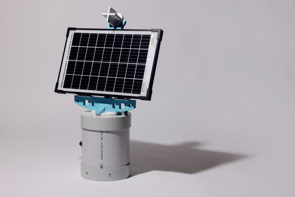 Electronic music device on wooden base featuring a white synthesiser keyboard with illuminated controls, connected to visible circuit boards.