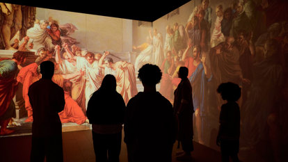 Silhouettes of people watching a projected display on a wall depicting the murder of Caesar in in ROME: Empire, People Power People Exhibition at Melbourne Museum