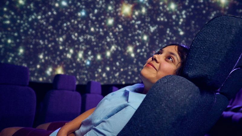 A Primary school student observes a projection of the stars on the dome of the Melbourne Planetarium 