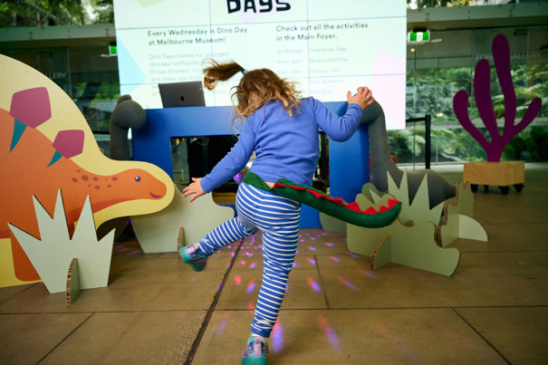 A child wearing a dinosaur tail dancing.