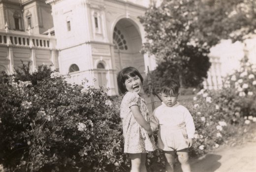 Two children near rose bushes outside Exhibition Building.