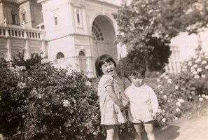 Two children near rose bushes outside Exhibition Building.