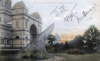 : Exhibition Building with lawn, trees and sundial in foreground.