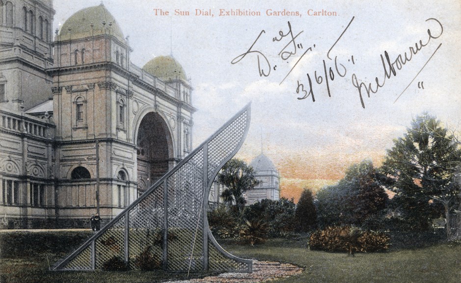 : Exhibition Building with lawn, trees and sundial in foreground.