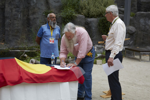 Three men signing papers