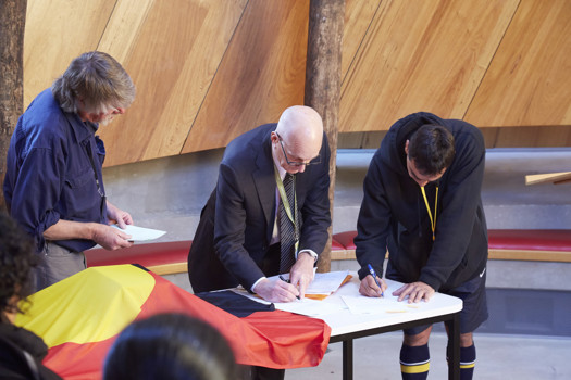 Two men signing papers