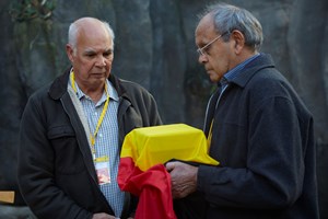 Two men. One man holding a box wrapped in the Aboriginal flag.