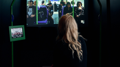 A woman watches a display in Identity: Yours, Mine, Ours exhibition at the Immigration Museum.