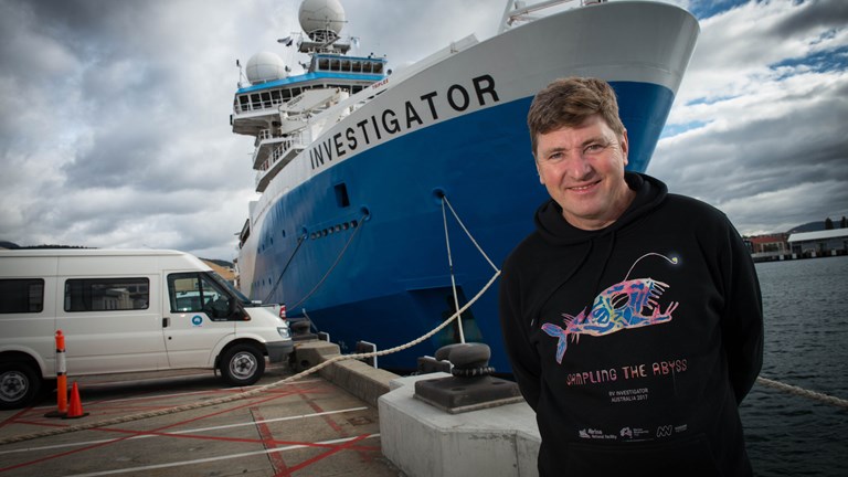 Museums Victoria scientist Tim O'Hara stands in front of the Marine National Facility research vessel <i>Investigator</i>.