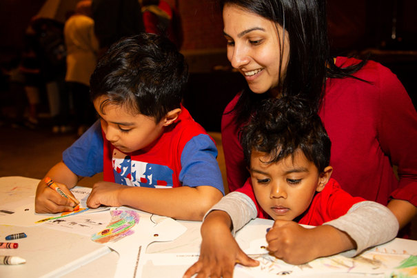  Woman and two boys participating in Colourful Dinos craft activities in the Pumping Station during the Little Kids' Day In at Scienceworks
