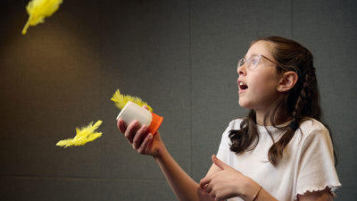 A young adult fires colourful feathers from an air cannon they have made during a Science Studio workshop at Scienceworks.