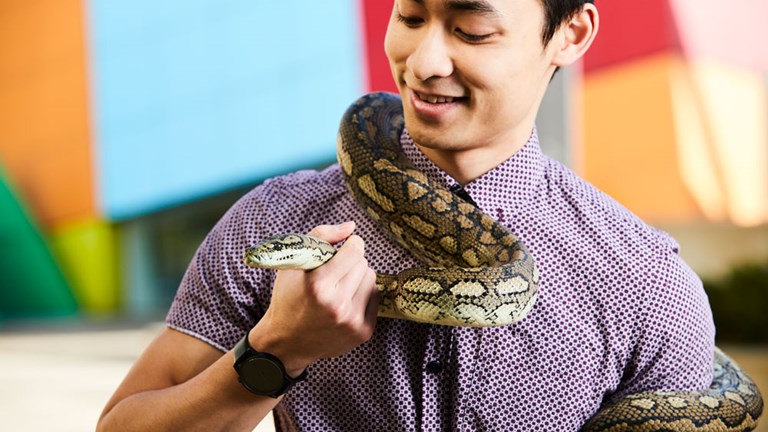 A man smiles whilst holding a snake