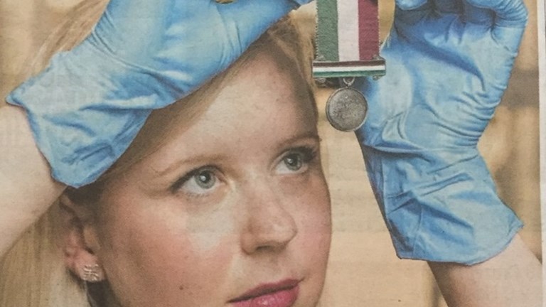 Woman wearing gloves holding a medal