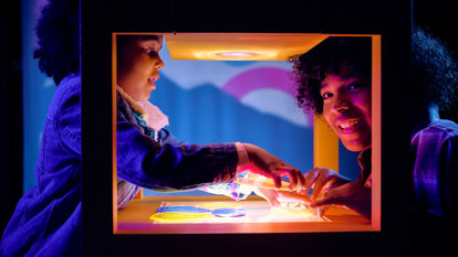 Two children moving transparent coloured shapes over each other to create different colours in Colour exhibition at Scienceworks.