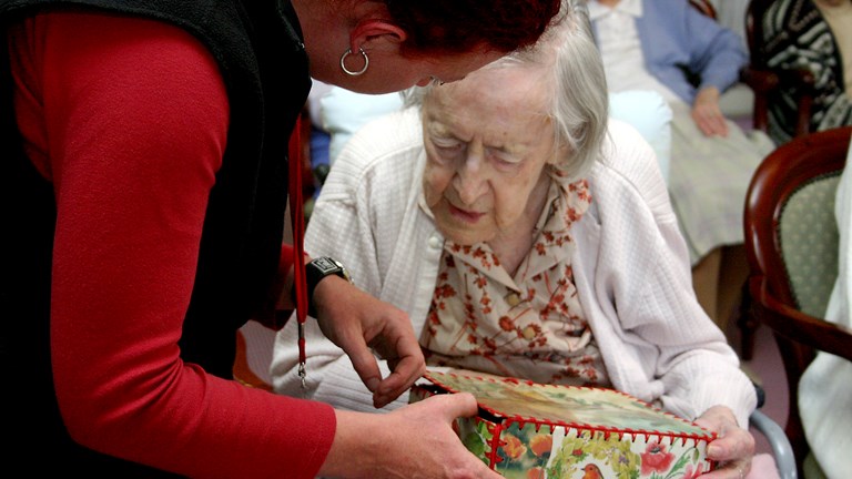 Museum staff showing box to an elderly woman 