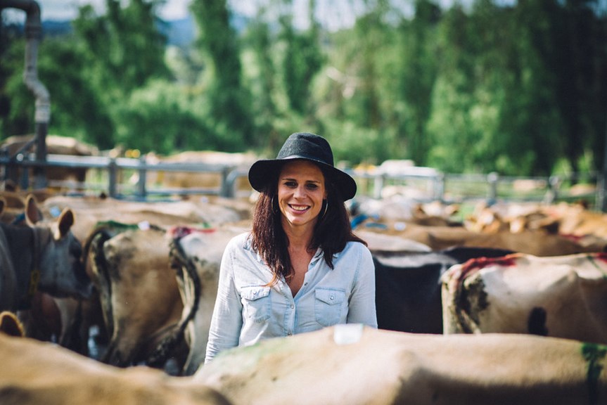 Woman standing in a cattle yard surrounded by cattle
