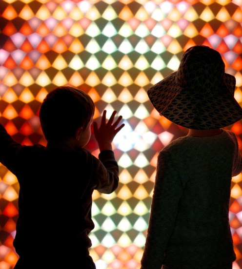Two children touch a brilliantly illuminated display at Melbourne Museum