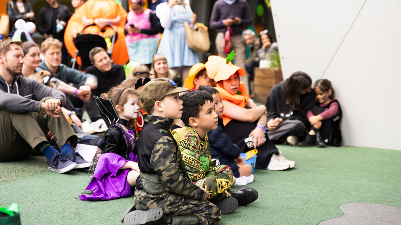 Families dressed in Halloween costumes learn about spooky science at a science show during Halloween at the Museum.