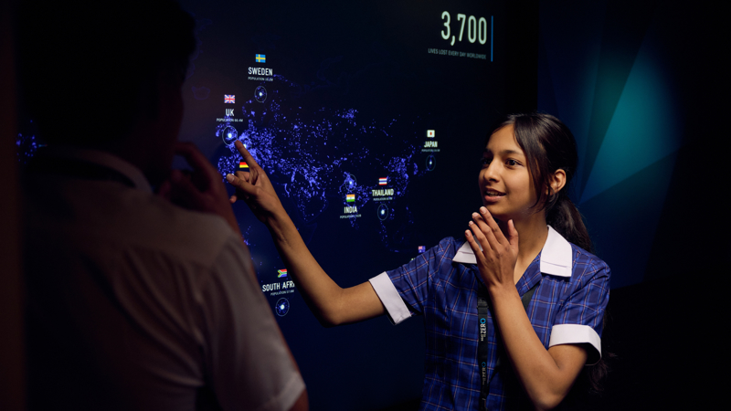 A student in the Road to Zero Experience Space pointing at a touch screen 