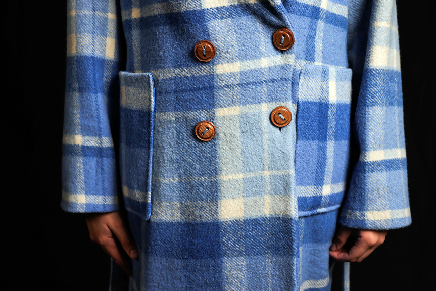 Close-up view of a blue and cream checked wool coat featuring wooden buttons.