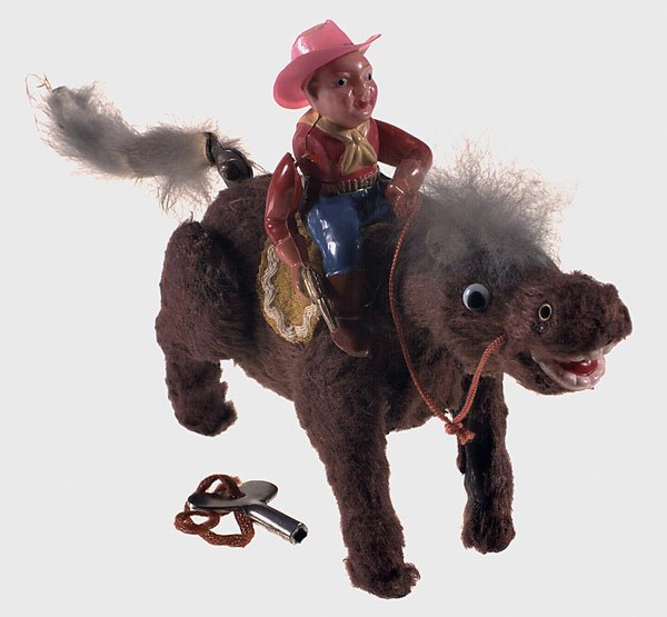 Toy horse with someone riding it who's wearing a hat
