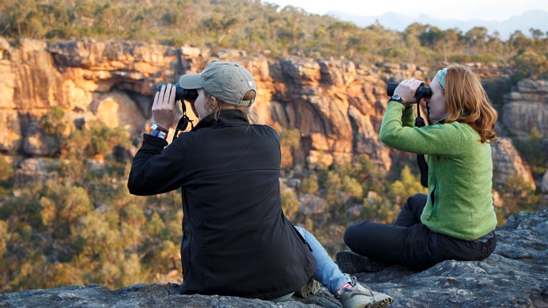 two women using binoculars outdoors