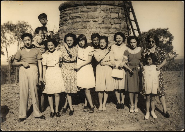 Gung family standing in front of stone wall and ladder. It was taken at Lake Mountain, circa 1930s-40s.  