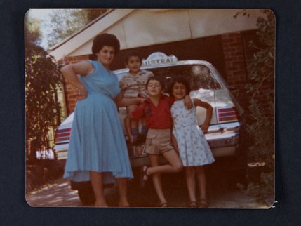 Portrait of a woman and three children standing in front of a taxi, ca. 1982. 