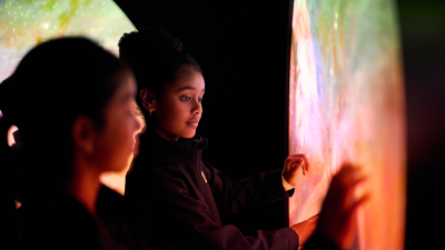 Students engages with an exhibit simulating black hole collisions n the Beyond Perception exhibition.