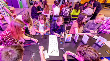 A group of adults at a make and take crafting table enjoy a fun activity at Nocturnal, Melbourne Museum