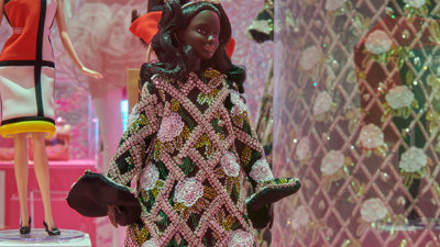 A barbie doll wearing a full length dress made of sequins.