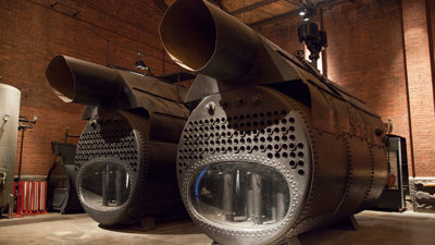 Two large boilers in a red brick building.