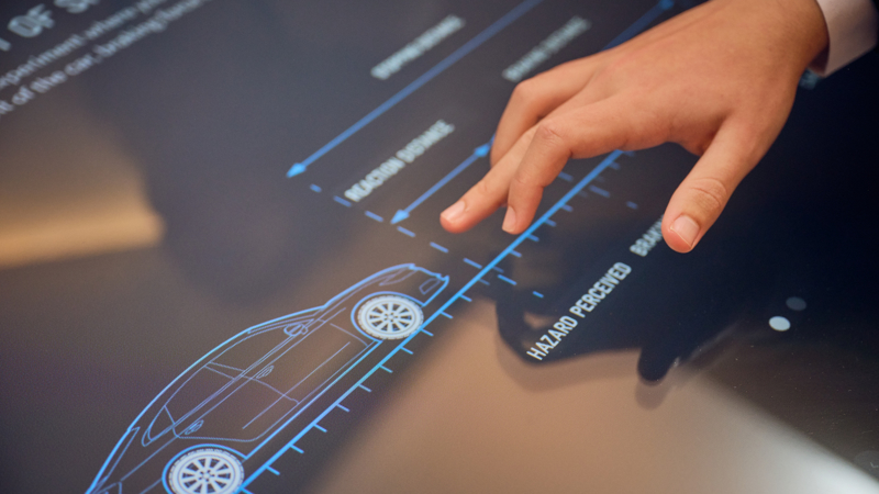 A touch table screen in the Road to Zero Learning Studio with an image of a car being touched by a student’s hand 