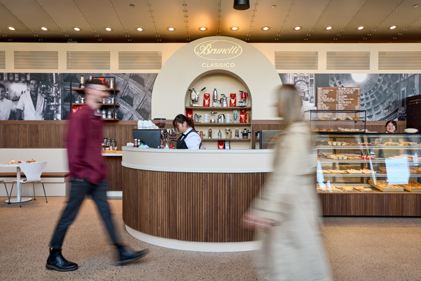 Two people walking past the service counter at Brunetti Classico