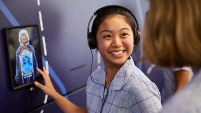 A student wearing headphones interacts with an iPad as part of Road Smart Interactive 