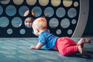 A baby looking at themselves in a group of circular mirrors