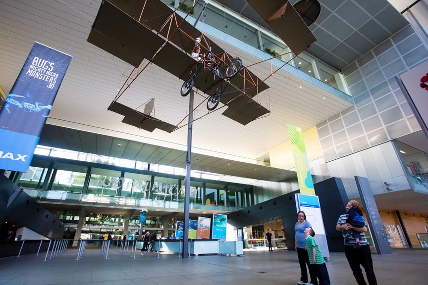 Family looking up at the Duigan biplane hanging in the Melbourne Museum foyer