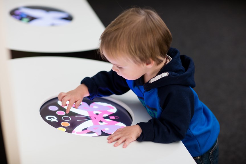 Toddler decorating a butterfly on an electronic screen in the Children's Gallery