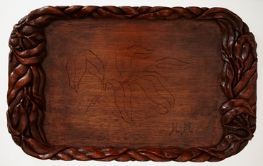 Hand-carved wooden tray, gum/leaf motif inscribed at centre and carved around edges. Initials 'H.M.' (Hilde Muffler) inscribed in bottom right corner. Made by Karl Muffler for his wife Hilde during his internment at Tatura Internment Camp between 1939 and 1944.