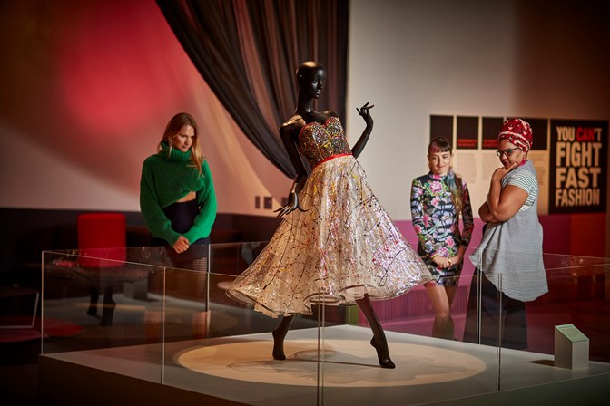 Three women looking at the Jenny Bannister 'Splash Plastic' dress on display in the 'You Can't Do That' exhibition at Melbourne Museum.