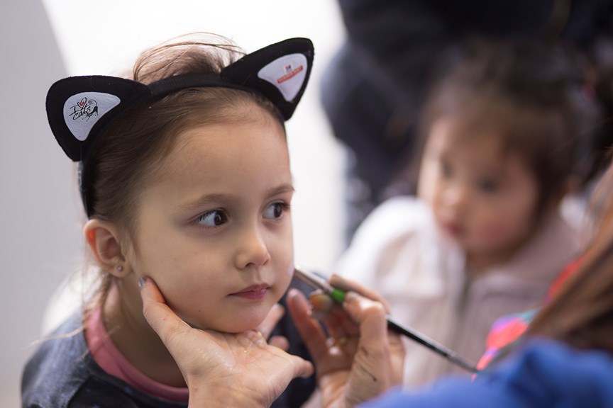 Child wearing cat-ears getting her face painted at Museum Members' Family Day, Melbourne Museum