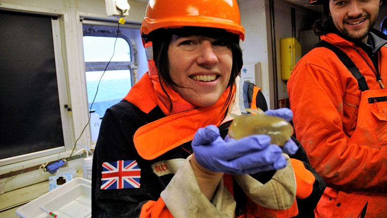 Melanie Mackenzie holding a marine invertebrate known as a Sea Pig during an Antarctic research voyage.