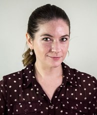 Portrait of woman wearing brown and white polka-dot shirt.