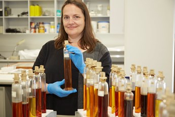 Woman holding bottles of liquid in a laboratory.
