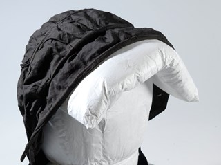 Black bonnet of 'calash' style, with rattan loops over crown that enable it to be folded back. 